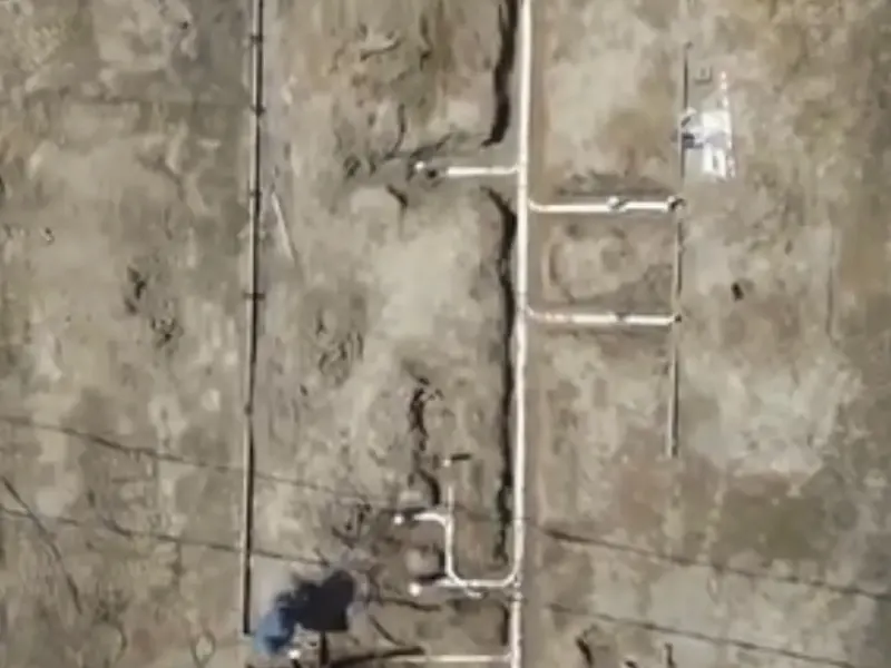 White PVC drain lines laid out across bare ground, seen from above, before a concrete slab is poured.