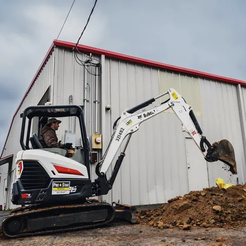 Mini excavator digging at commercial building, from Ledbetter Plumbing’s own photographs.