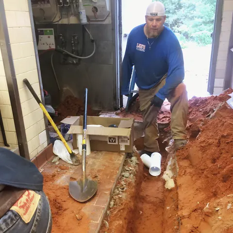 Technician in sewer trench inside building, from Lee's Plumbing’s own photographs.